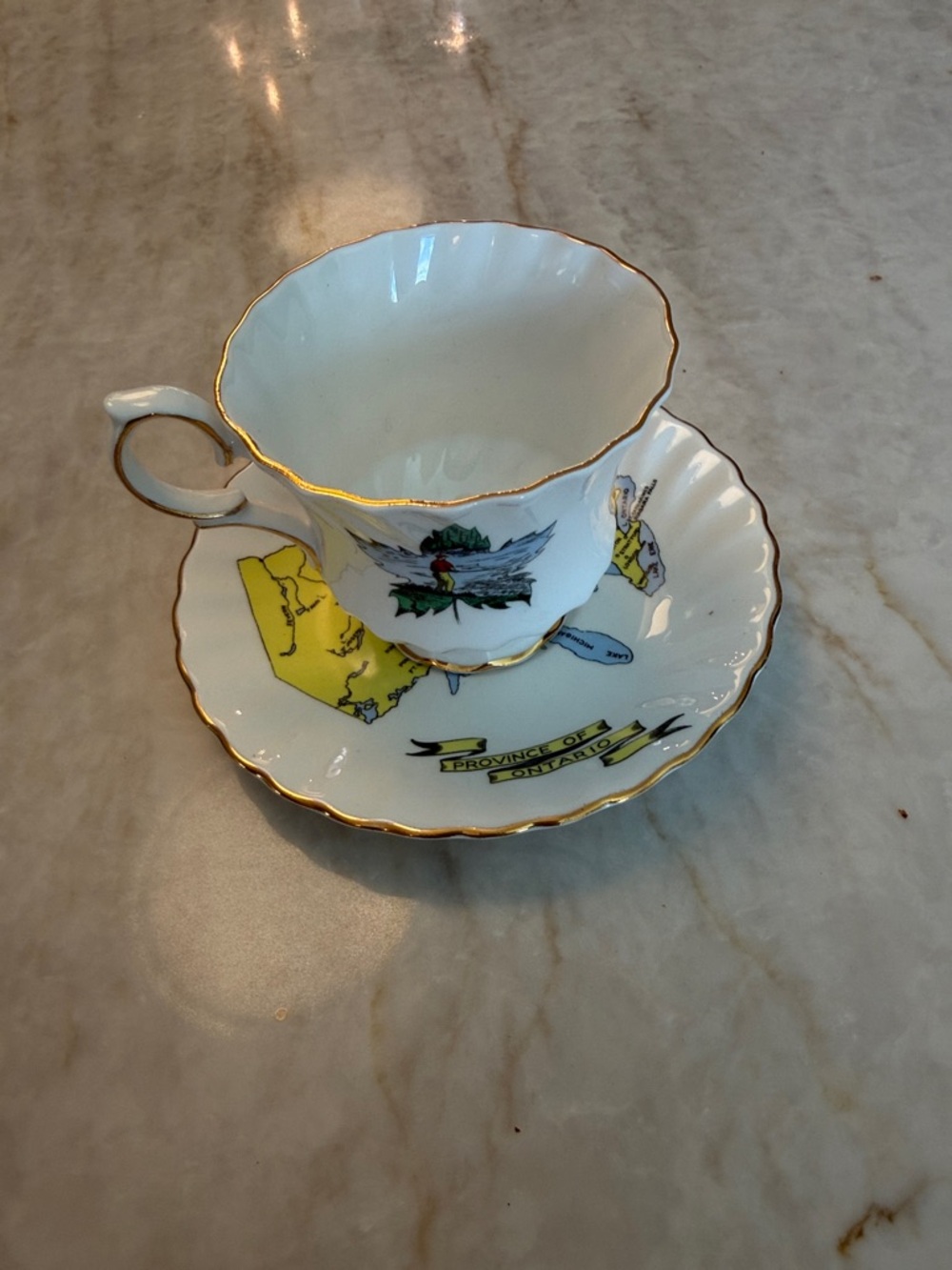 White Porcelain Teacup and Saucer with Gold Trim and Yellow Map Accents